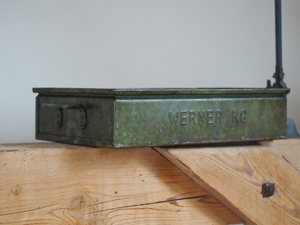 Metallkiste in grün steht auf Holzbalken und soll helfen Ordnung zu schaffen